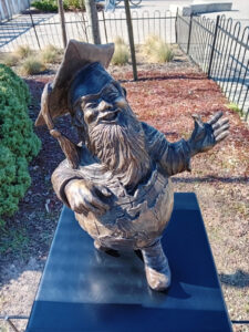 Krasnal wrocławski ubrany w globus, ustawiony na postumencie.