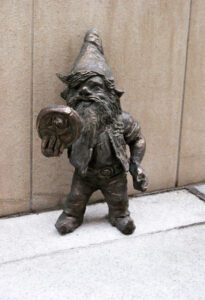 Krasnal, figurka z brązu na tle budynku