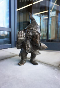 Krasnal Wietrzysław stojący przy turbinie wiatrowej przed siedzibą VSB Energie Odnawialne Polska we Wrocławiu