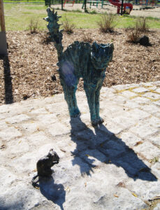 Rzeźba przedstawia kota w ekspresyjnej pozie – wyraźnie przestraszonego małą myszką. Kot ma wygięty grzbiet, uniesiony ogon i lekko wyciągnięte łapki. Figura ustawiona jest w parkowej przestrzeni miejskiej w Trzebnicy, na kostce granitowej wśród alejek parkowych.