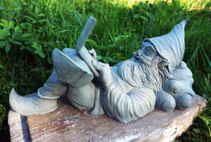 Krasnal Wrocławski leży oparty o chmurkę z otwartym laptopem