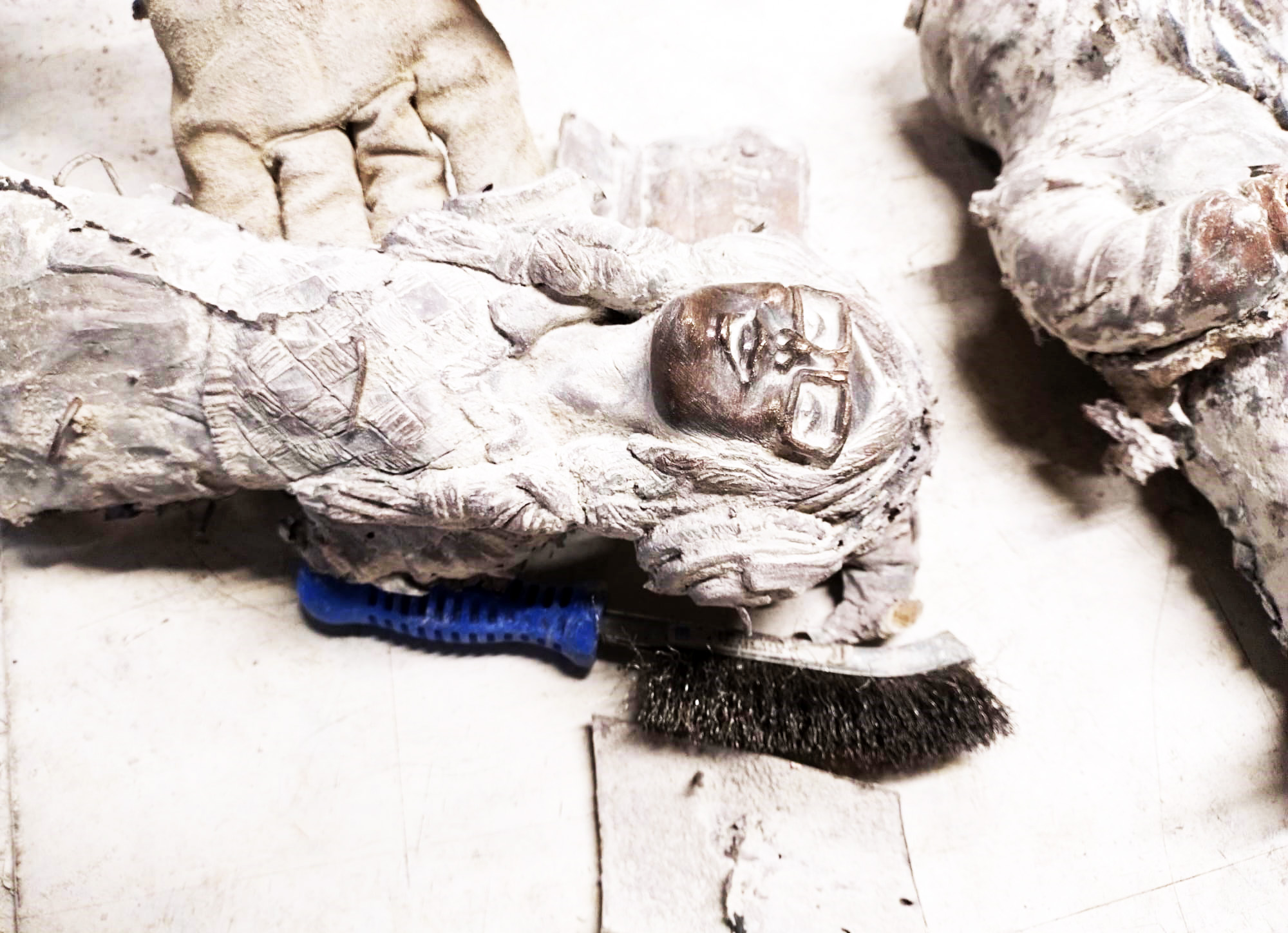 Zdjęcie przedstawia świeżo dwa odlewy z brązu figurek krasnali, są pokryte białym gęstym nalotem, reszkami gipsu i piasku kwarcowego.